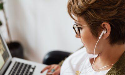 Focused woman using laptop and listening to music in earphones · Free ...